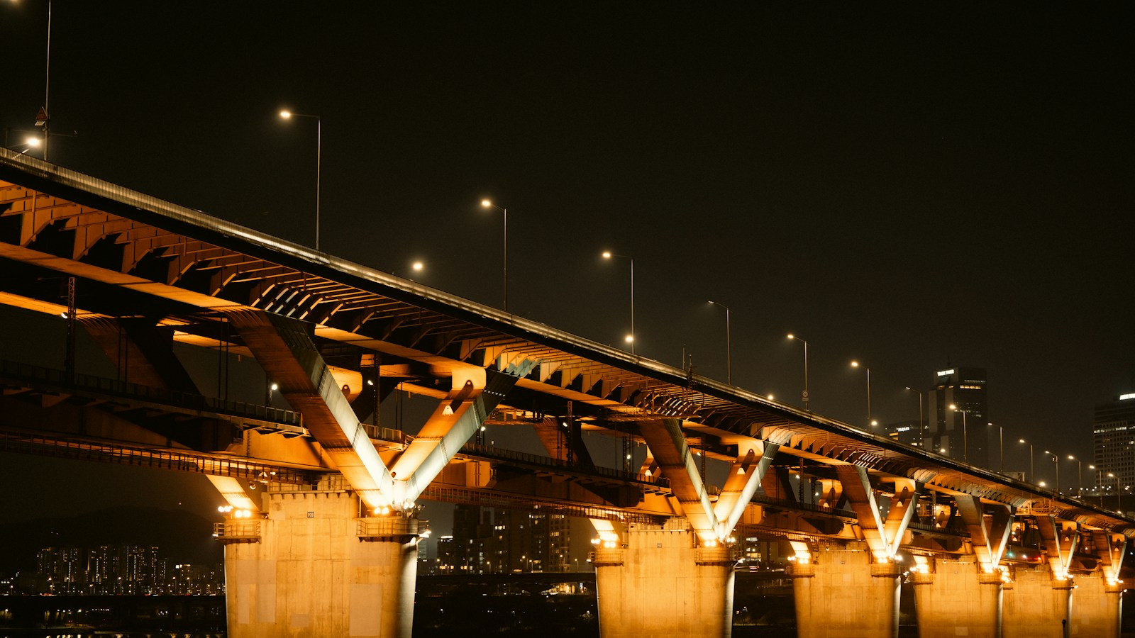 A Han River bridge lit in orange at night in Seoul