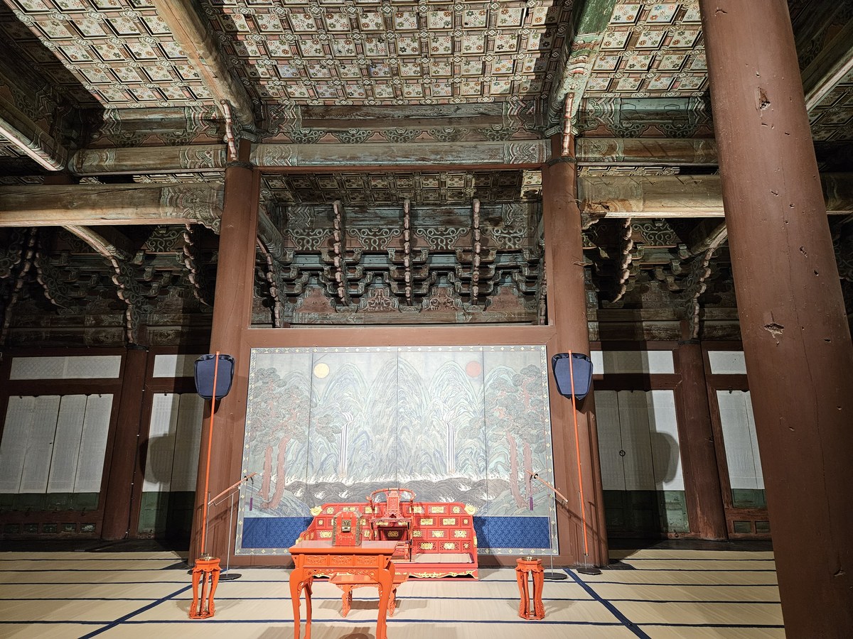 The royal throne inside Geunjeongjeon hall at night, lit up, with the Irworobongdo screen of the sun, moon and five peaks