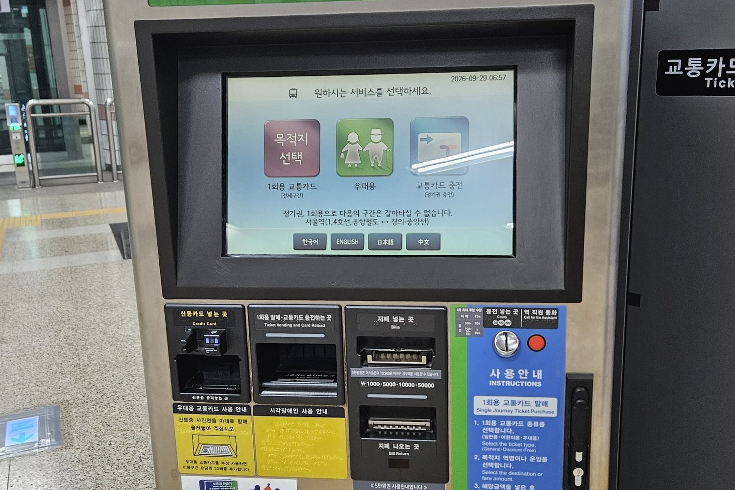 Older stainless Seoul subway ticket machine with a small screen showing three Korean options, single-journey ticket, free ticket and card reload, above slots for a credit card, a ticket and card reload tray, bills marked 1,000, 5,000, 10,000 and 50,000 won, and coins, with a blue instruction panel