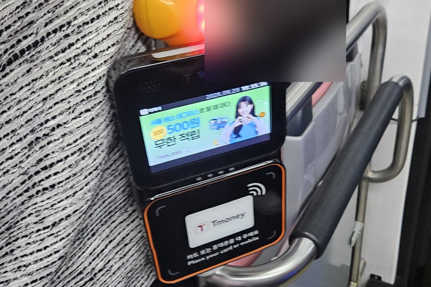 T-money card reader by the door of a Seoul bus, with a reader pad labelled Tmoney and the words Place your card or mobile in Korean and English