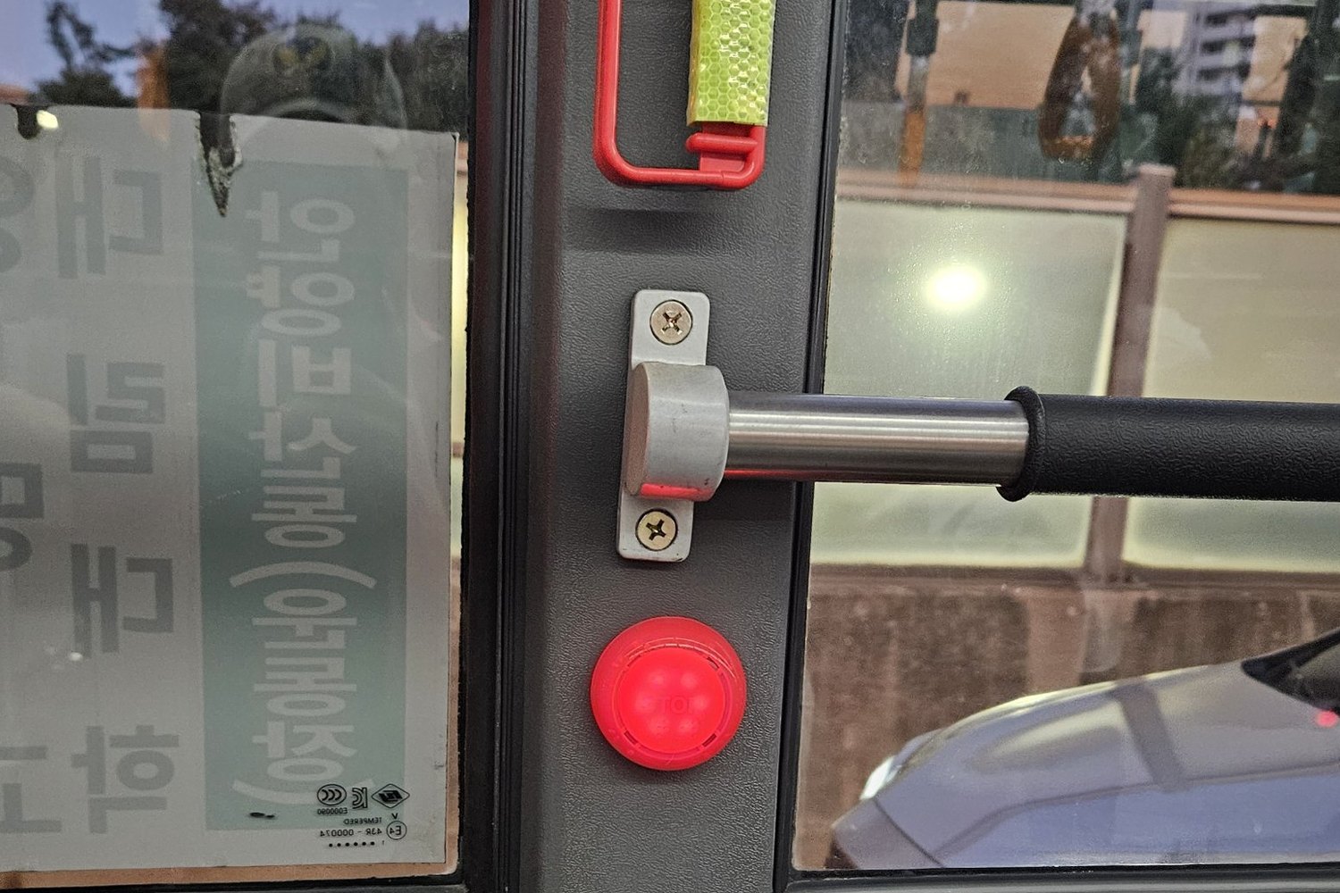 A red stop-request button on a pillar inside a Seoul city bus