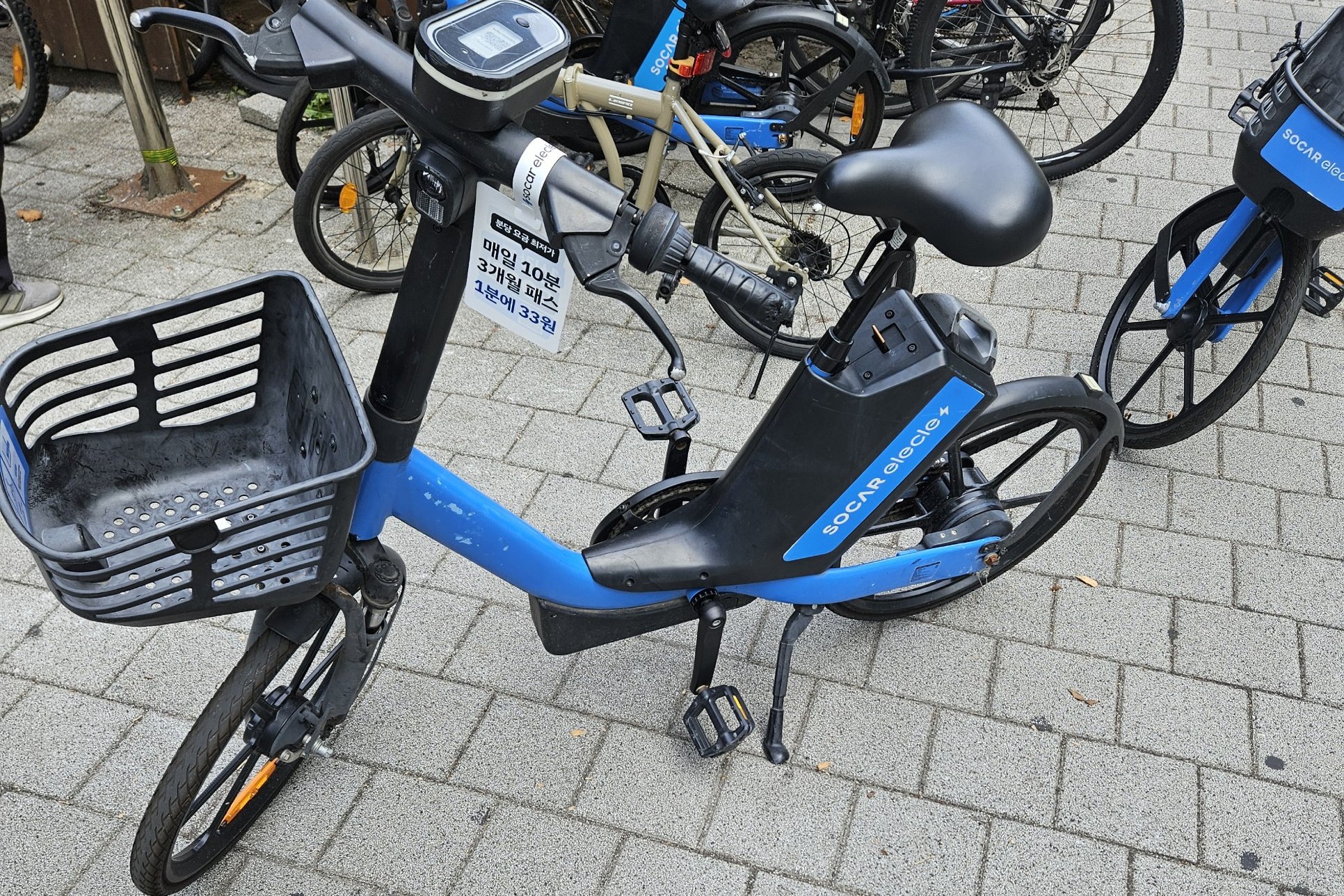 A blue SOCAR elecle e-bike parked on a Seoul sidewalk