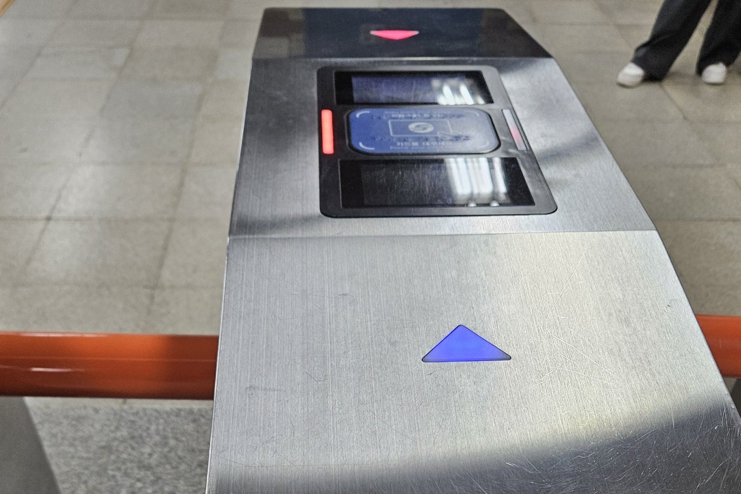 Stainless steel Seoul subway ticket gate seen from above, with a blue card reader in the middle and a blue arrow showing the way through