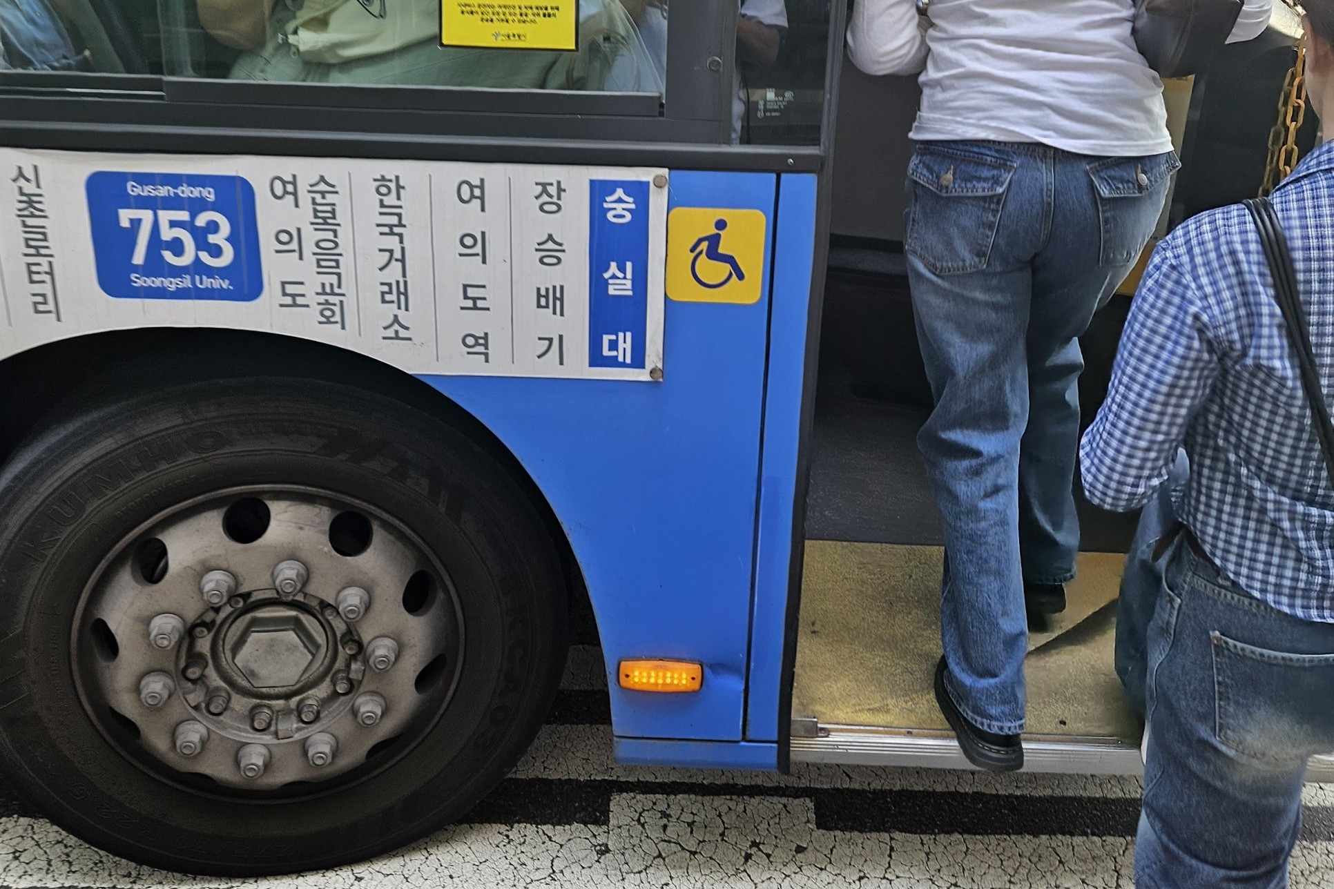 Passengers stepping onto a blue Seoul trunk bus, route 753, beside its route panel, Sept 2026