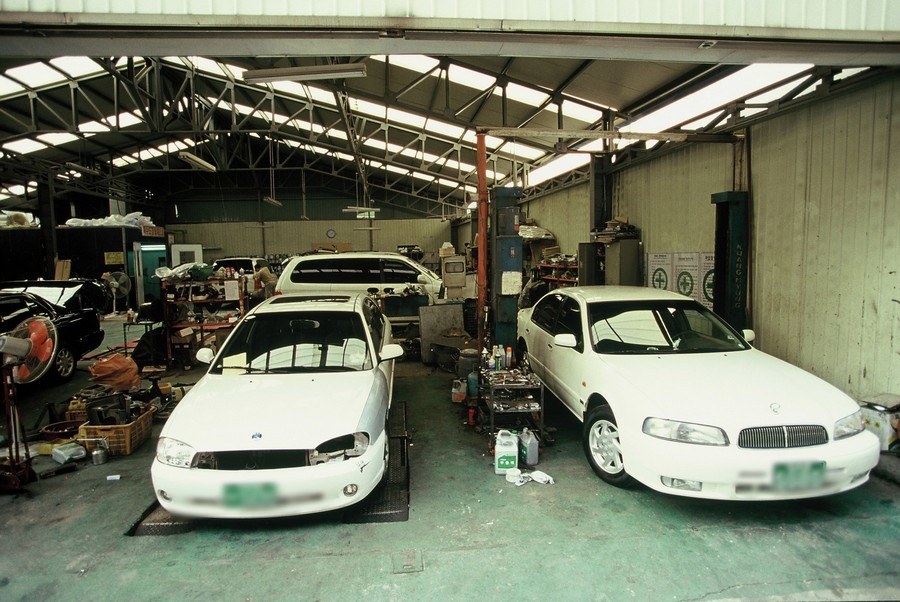 Inside a large car repair garage in Seongsu-dong in 2005, white sedans parked with tools and parts around them