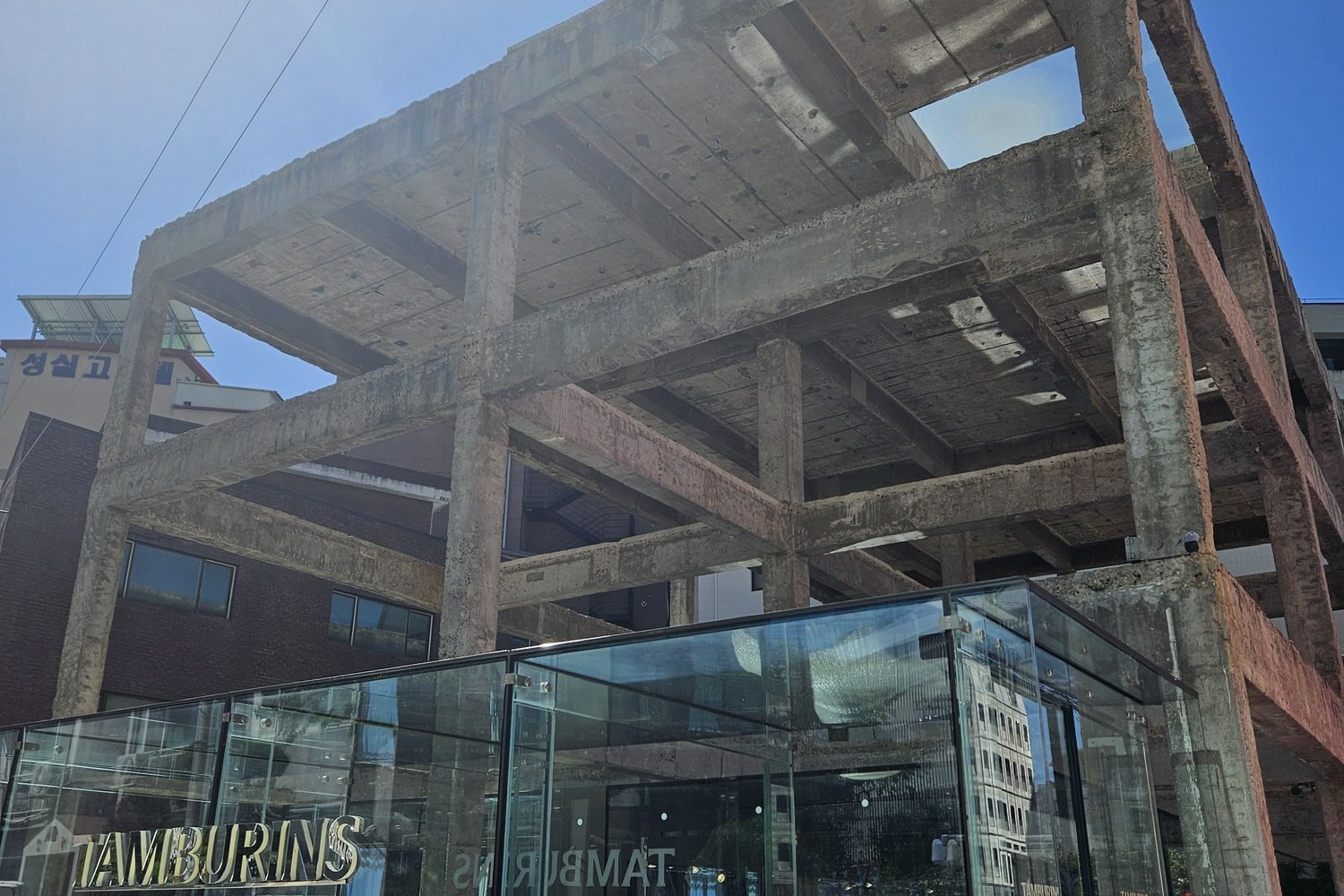 A glass-walled store built inside a bare concrete frame on a Seongsu street
