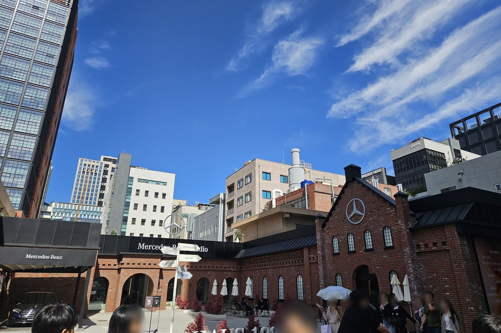 A red-brick building with arched windows and a wide paved forecourt full of visitors in Seongsu
