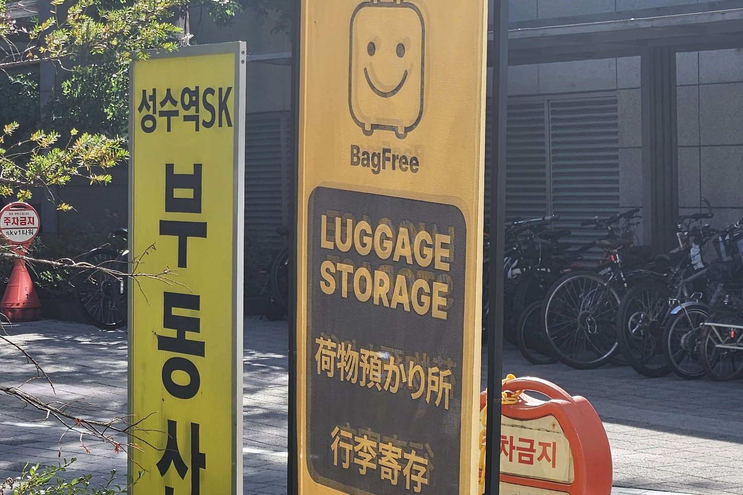 Yellow sign for a 24-hour luggage storage near Seongsu Station, in English, Japanese and Chinese