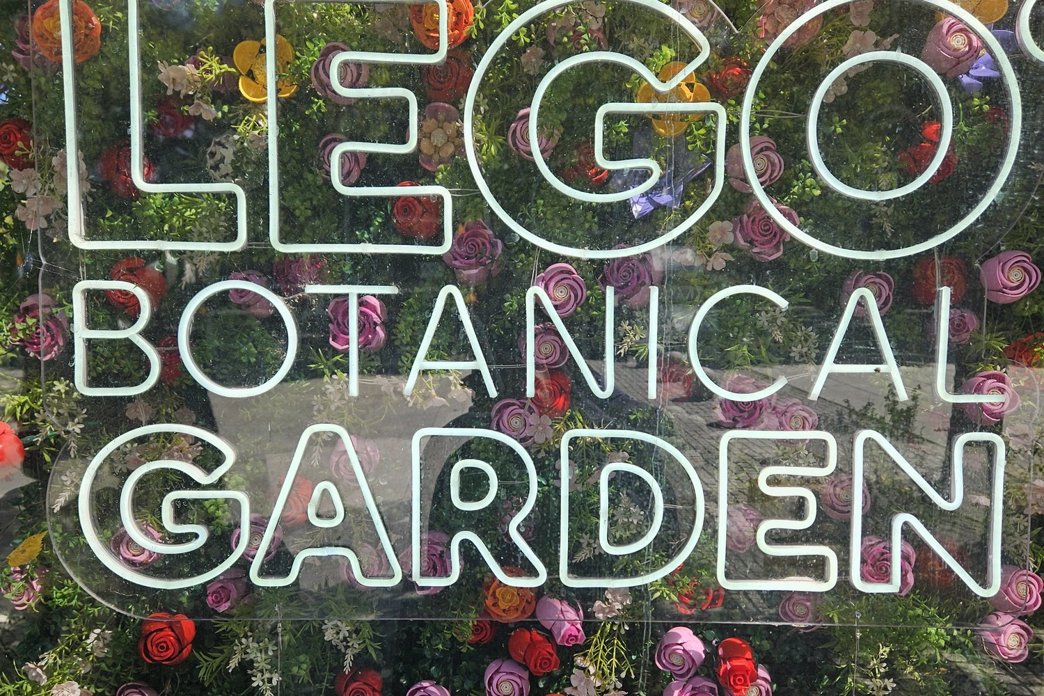 A wall of LEGO flowers behind a neon sign reading LEGO Botanical Garden at Seoul Forest