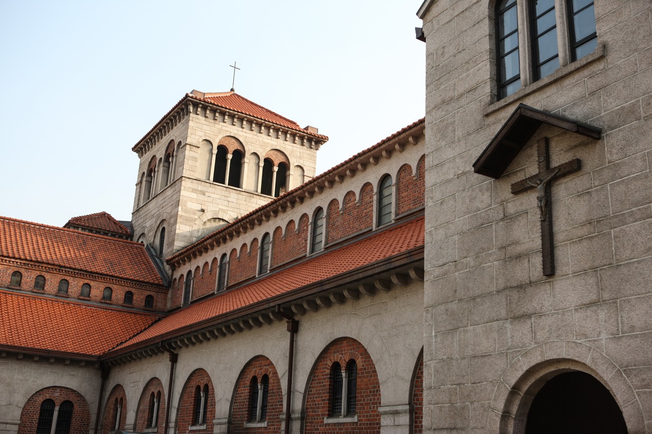 The Seoul Anglican Cathedral's grey stone bell tower, red brick walls and red tile roofs under a clear sky