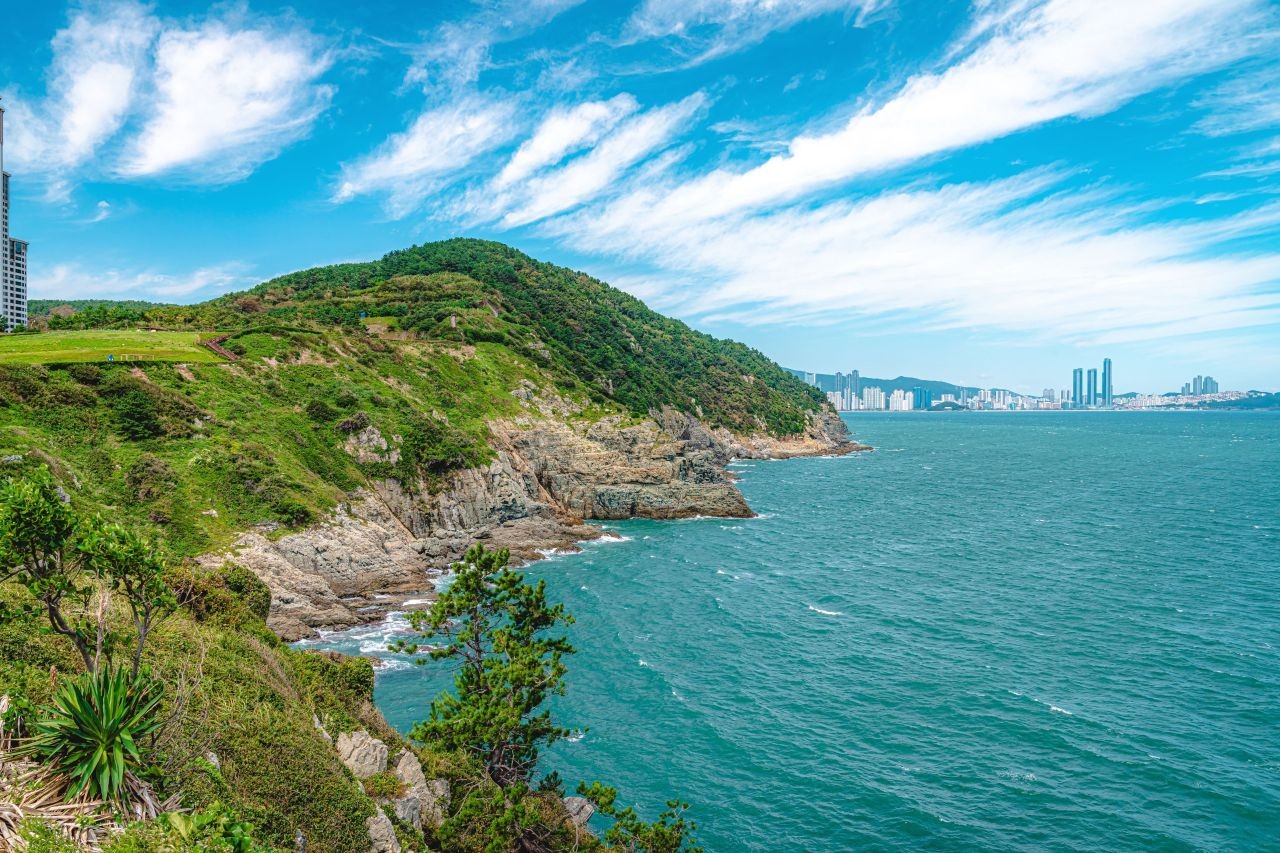 The Oryukdo rocks and the green headland of Yongho-dong in Busan seen from the coast on a sunny day