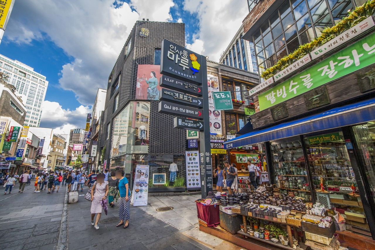 Insadong-gil street in Jongno-gu on a sunny day, with shop signs, a craft shop display and people walking
