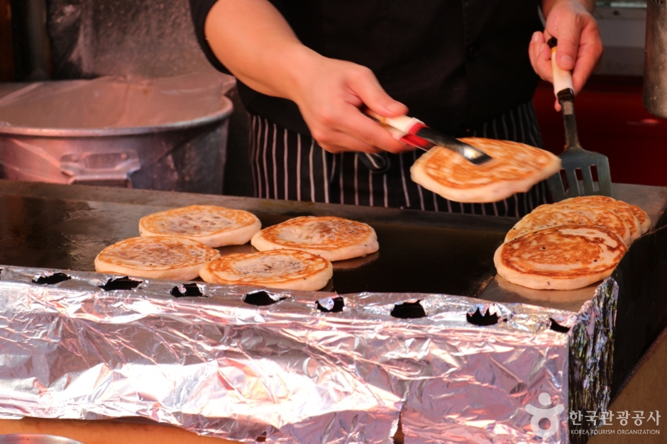 Hotteok pancakes being flipped on a griddle at a Namdaemun Market stall