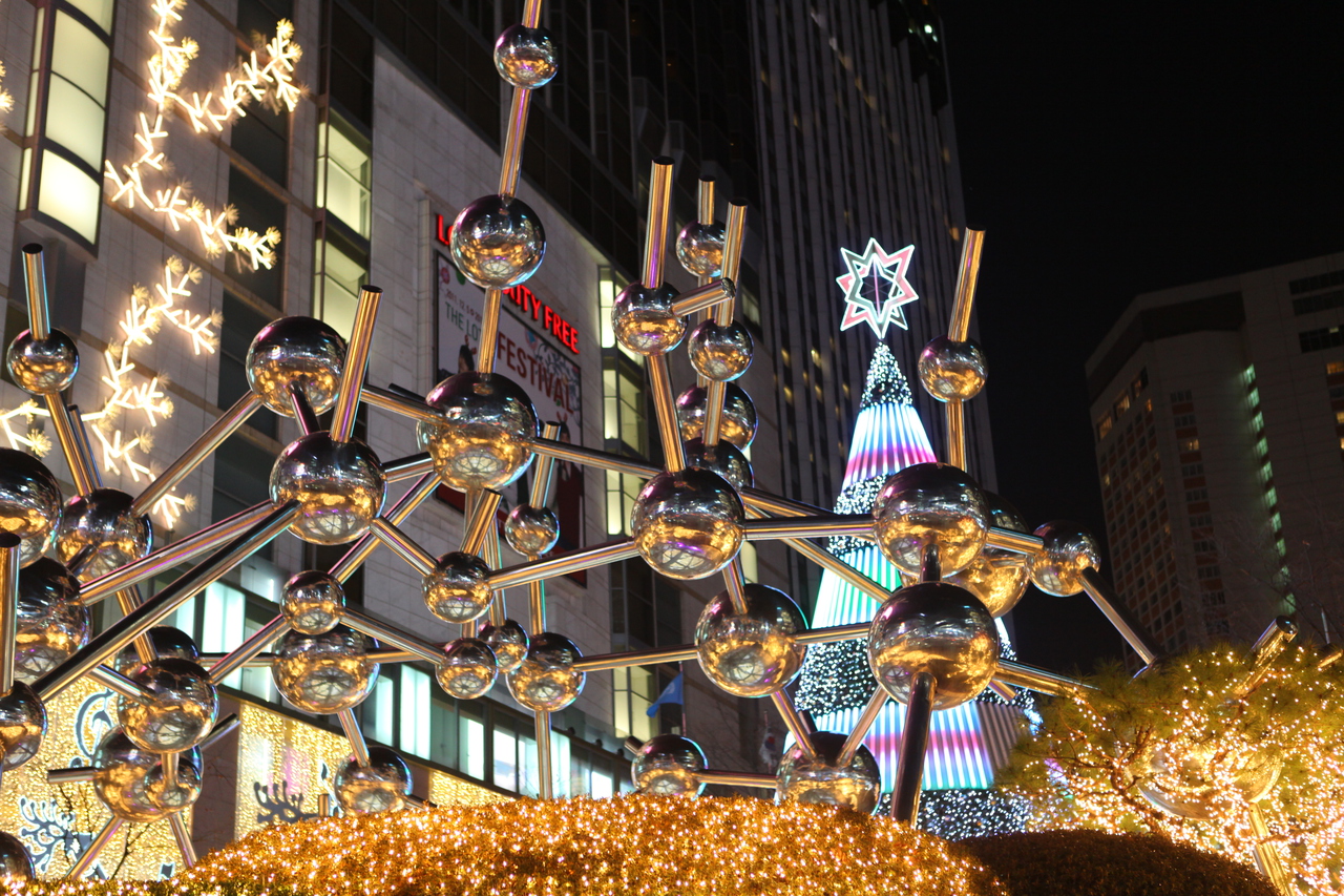 Lotte Department Store's Myeongdong building at dusk, wrapped in warm Christmas lights and decorated trees