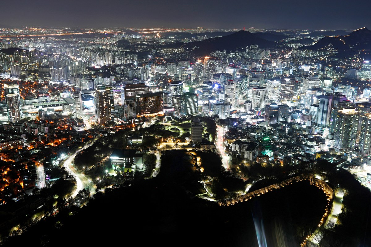 Night view over Seoul from Namsan with city lights and the lit stone fortress wall winding below