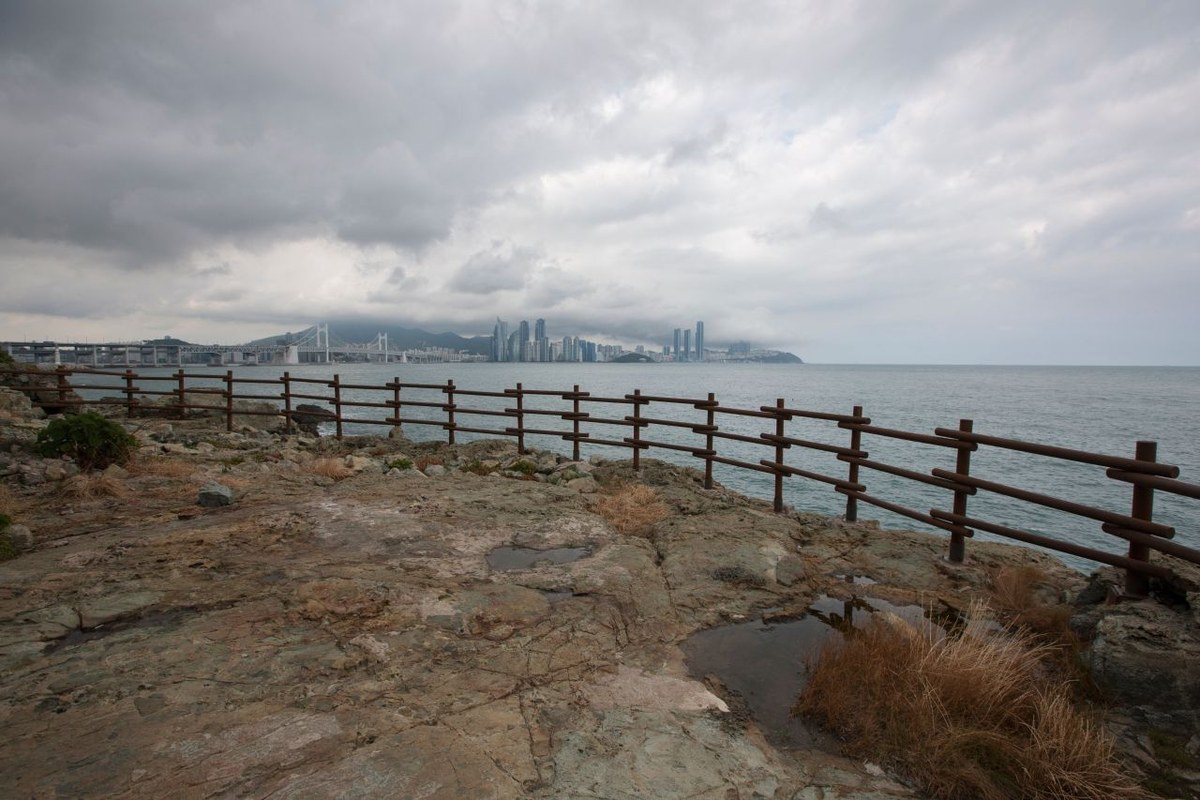 Cliffs of the Igidae coast in Busan meeting the sea, with a walking path along the top