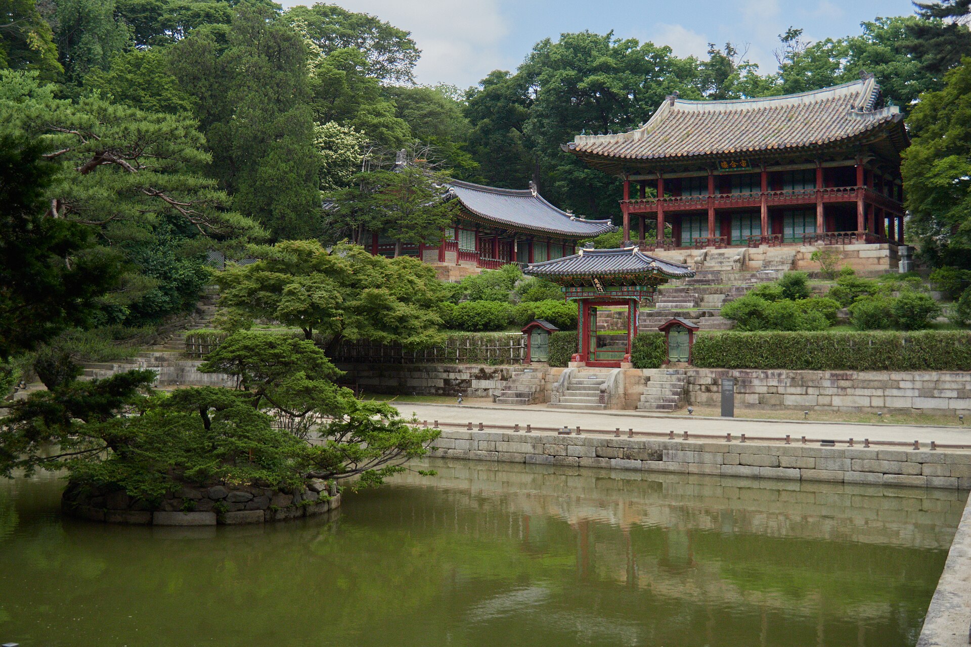 Juhamnu pavilion and the surrounding garden buildings of Changdeokgung, seen across the rectangular Buyongji pond in summer greenery
