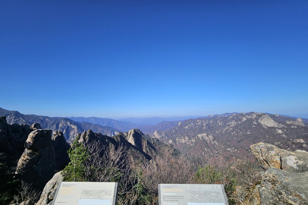 Mountain ridges in Seoraksan National Park seen from the Bongjeongam viewpoint, with trail information boards in the foreground