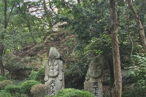 Two stone guardian posts carved with Chinese characters beside a paved path in a forest near Bukhansan